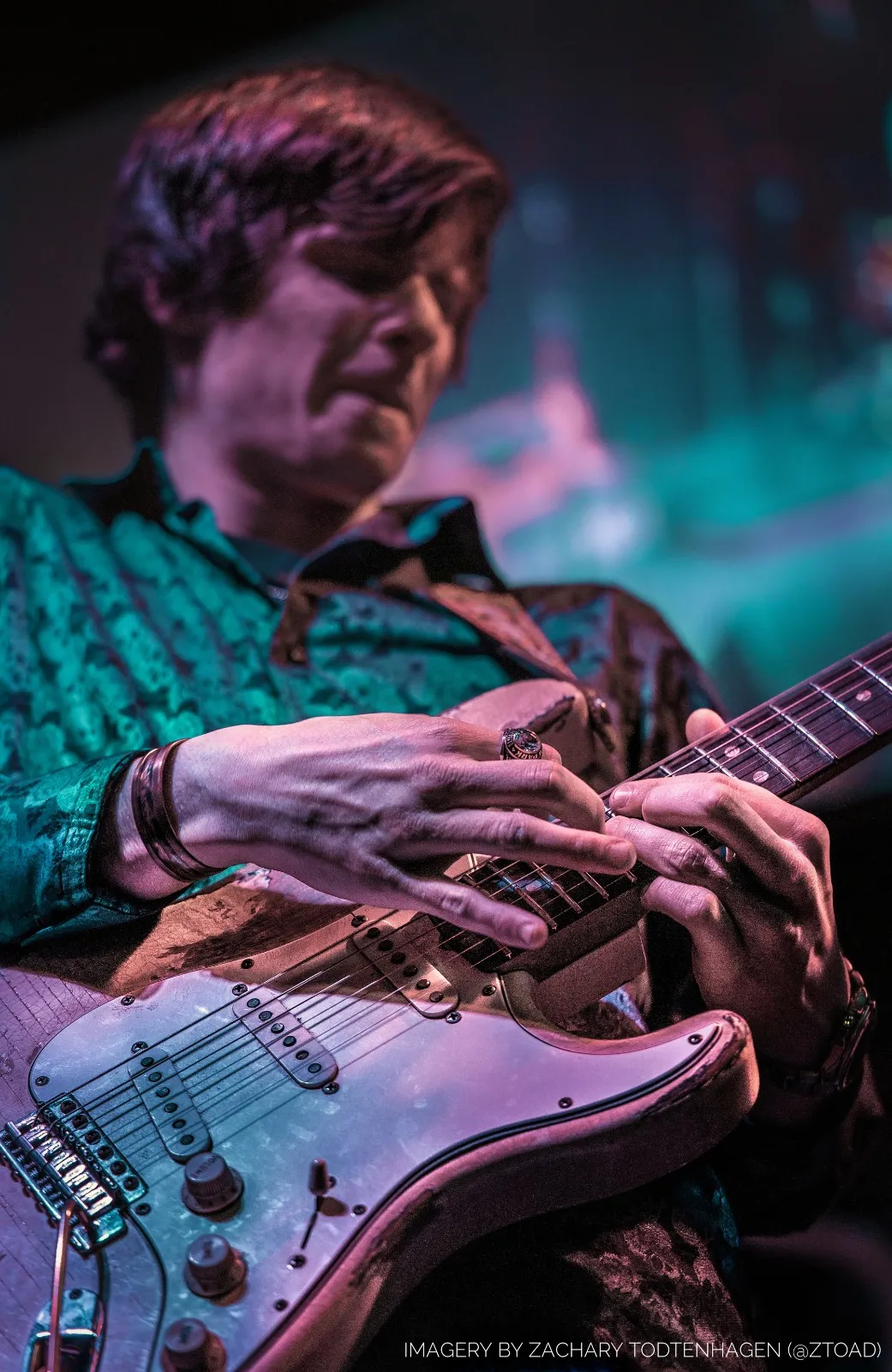 Hayden Fogle's hands on the neck of a road-worn Stratocaster, bending a string, a heavy ring on one finger.